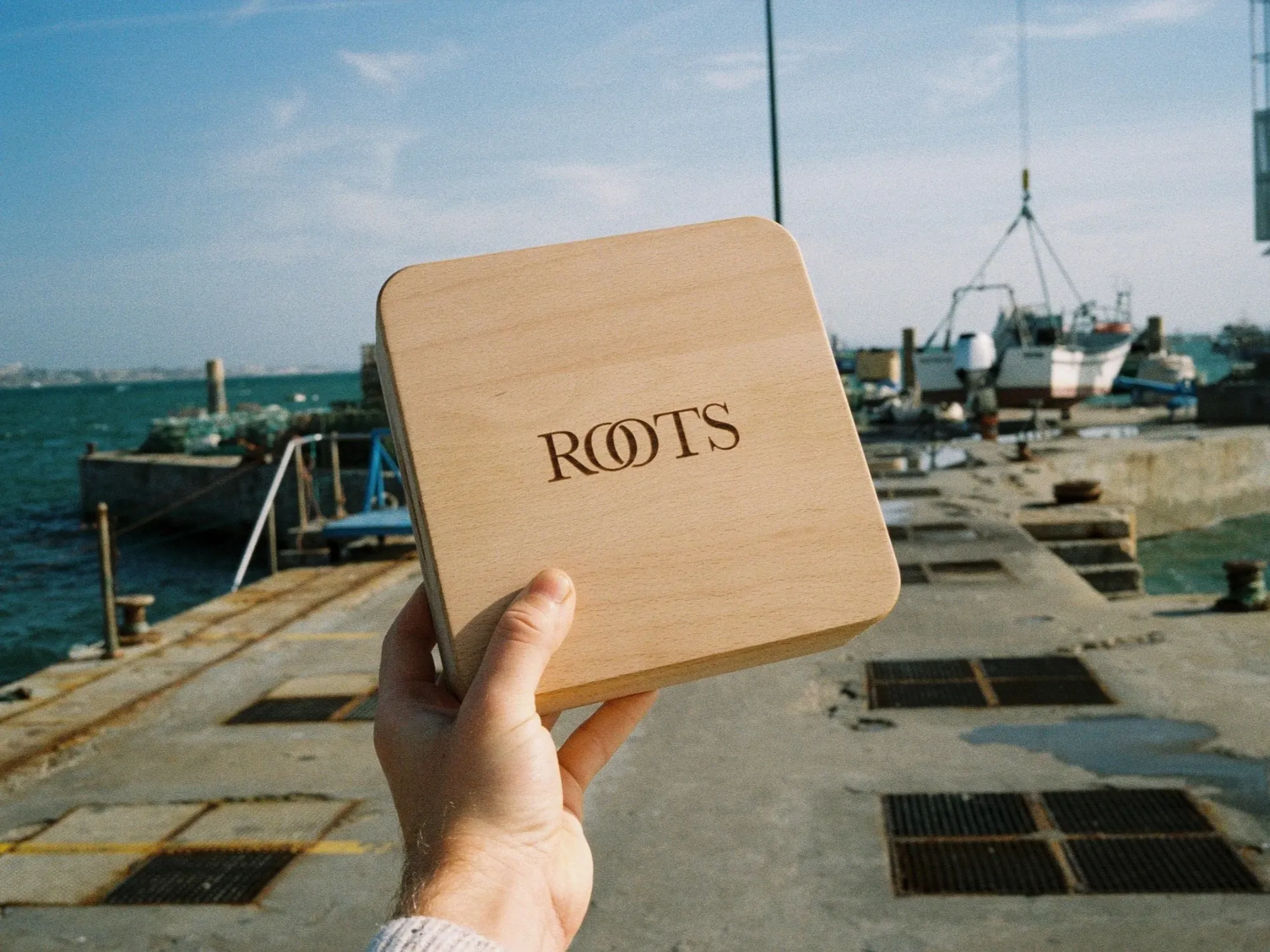 Schneidebrett aus Buche mit eingraviertem Schriftzug ROOTS, gehalten am Hafen